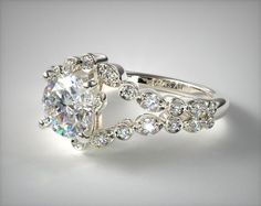 a white gold ring set with an oval cut diamond surrounded by smaller round diamonds