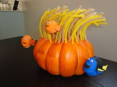 an orange pumpkin sitting on top of a wooden table next to two small blue fish