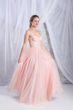 a beautiful young woman in a pink dress posing for the camera with her hands on her hips