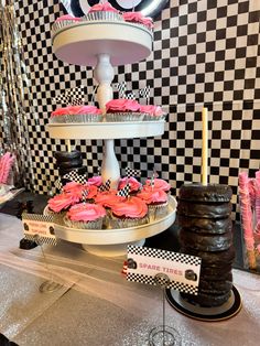 a table topped with three tiered cakes and cupcakes