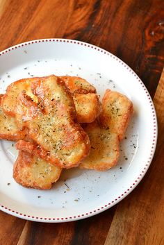 small pieces of bread on a plate with seasoning sprinkled on top, sitting on a wooden table