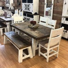 a dining room table with two benches and some cupboards in front of it on a wooden floor