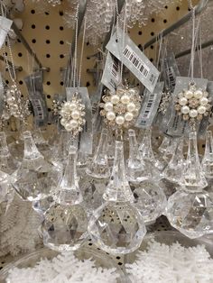 many wine glasses are hanging from the ceiling with pearls and bows on them in a store