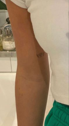 a woman's arm with a small tattoo on the left side of her arm