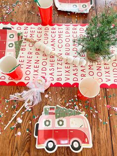 a table topped with plates and cups filled with confetti next to a christmas tree