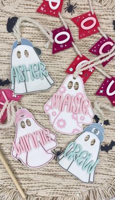 four halloween tags with the word ghost hanging from strings on a table next to other decorations