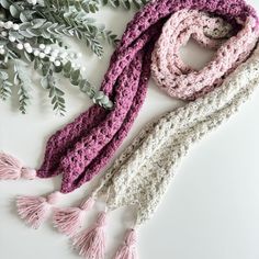 two crocheted scarves with tassels are laying on a white surface