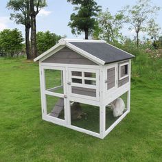 a white chicken coop in the middle of a grassy field