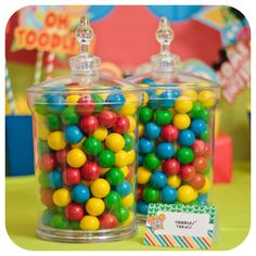 two glass containers filled with colorful candy on top of a table