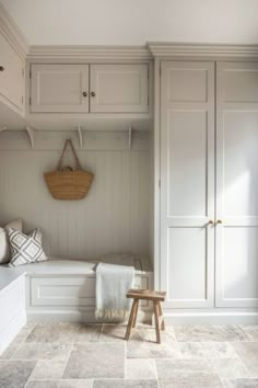 a white bench sitting in the middle of a room next to a wall mounted coat rack