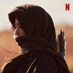 a woman wearing a brown scarf and holding a bird in her hand with the words no written on it