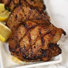 grilled chicken with lemon wedges on a white plate