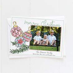 two children sitting on a bench in front of a christmas ornament and bauben