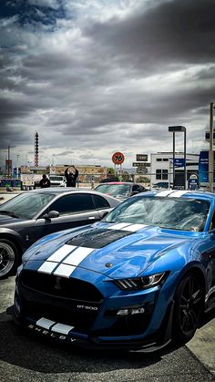 several cars parked in a parking lot under cloudy skies