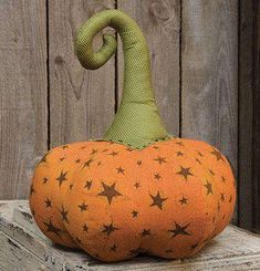 an orange pumpkin sitting on top of a wooden table next to a fence with stars