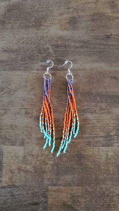 an orange and blue beaded earrings on a wooden surface