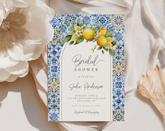 a blue and white wedding card with lemons on it next to some flower petals