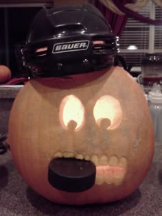 a hockey helmet on top of a pumpkin with eyes and mouth shapes carved into it