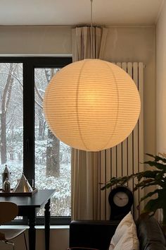 a living room filled with furniture and a large white ball light hanging from the ceiling