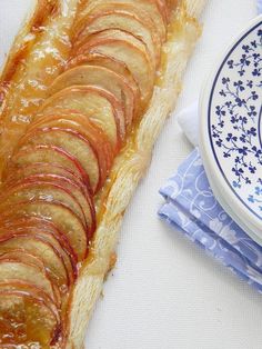 a pastry on a plate next to a blue and white flowered napkin with a bowl