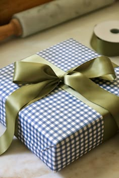 a blue and white checkered gift box with a green ribbon on it next to a roll of toilet paper