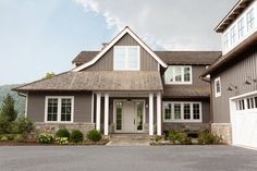 a gray house with white trim and two garage doors on the front, and three windows in the back