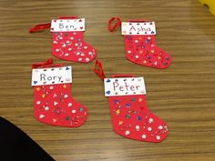 four red christmas stockings with name tags on them sitting on a wooden table next to a banana