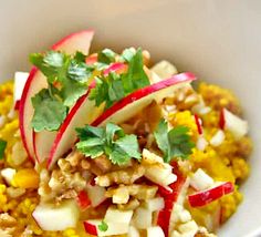 a white bowl filled with food and garnished with cilantro, apple slices and parsley