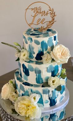 a blue and white wedding cake with flowers on top