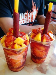 two cups filled with ice cream and fruit on top of a table next to each other