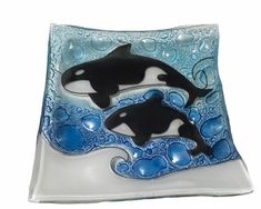 two black and white orca killer whales on blue swirled glass plate with bubbles