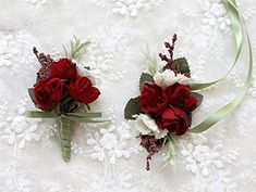 two red and white flowers are sitting on a lace tablecloth