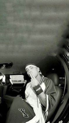 a man sitting in the back seat of a car with his hands to his mouth