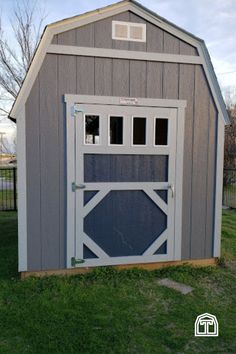 a small gray and white shed sitting in the grass