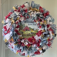 a welcome to our home wreath hanging on the front door with red, white and blue fabric