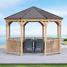 a wooden gazebo sitting on top of a lush green field next to the ocean