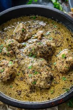 a pan filled with meatballs covered in gravy and garnished with parsley