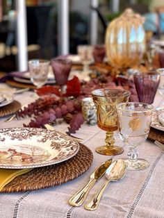 the table is set with dishes, glasses and silverware for an elegant dinner party