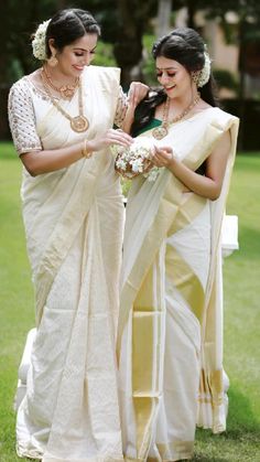 two women standing next to each other in white sari