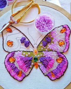 a close up of a butterfly on a hoop with beads and scissors next to it