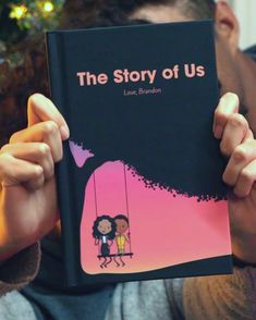 a person holding up a book in front of their face with the title, the story of us