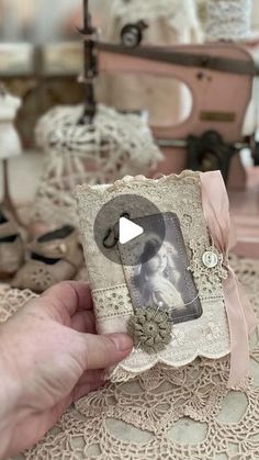 someone is holding an old photo in front of some lace doily on a table