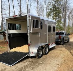 a horse trailer parked on the side of a dirt road