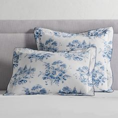 two blue and white pillows sitting on top of a bed