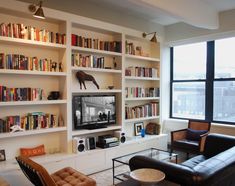 a living room with bookshelves and couches in front of a flat screen tv