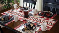 the table is set with black and red placemats, plates, cups, and utensils