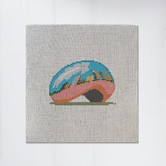 a cross - stitch picture of a mushroom with mountains in the background on a white wall