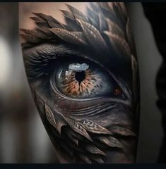 an eye with feathers on it is seen in this tattoo design by the artist,