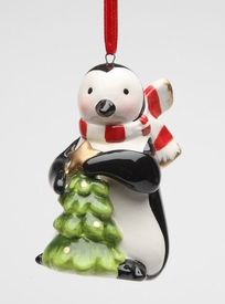 a glass ornament with a penguin holding a christmas tree