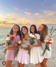 four girls standing on the beach with flowers in their hands